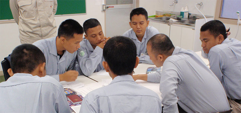 Technical trainees listen to a veteran operator's explanation